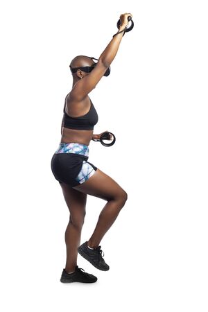 Athletic black female playing a vr video game pretending to do mountain climbing in virtual reality.  She is gaming while exercising to depict technology and healthy activities.の写真素材