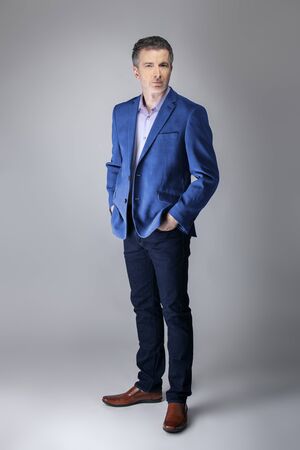 Middle-aged Caucasian businessman looking posh wearing modern fall collection style blue jacket.  Depicts confident and mature stylish fashion.  Shot in studio for catalog look.の写真素材