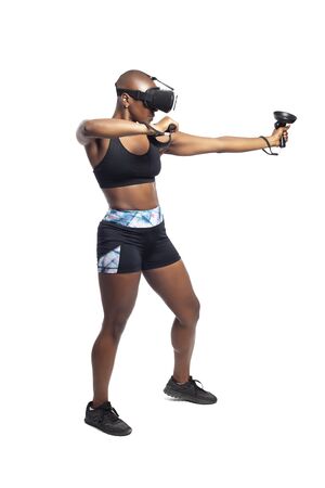 Black female wearing virtual reality headset pretending to draw a bow and playing a VR archery video game.  She is aiming at a target. Depicts esports.の写真素材