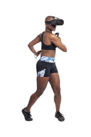 Black African American woman working out by playing a VR dancing rhythm video game while wearing a virtual reality headset.  Depicts esports technology and active lifestyle.の写真素材