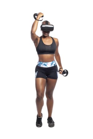 Black African American woman working out by playing a VR dancing rhythm video game while wearing a virtual reality headset.  Depicts esports technology and active lifestyle.の写真素材