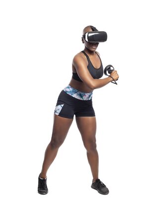 Black African American woman working out by playing a VR dancing rhythm video game while wearing a virtual reality headset.  Depicts esports technology and active lifestyle.の写真素材