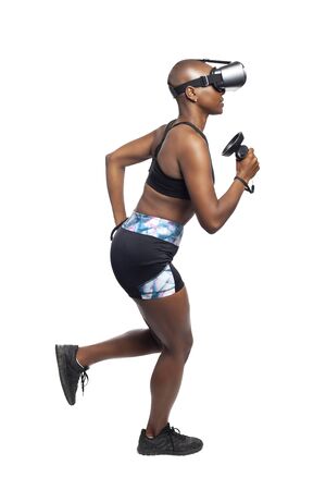 Black African American female running in VR while wearing a virtual reality headset for training or playing a video game.  Depicts technology and sport and esports.の写真素材
