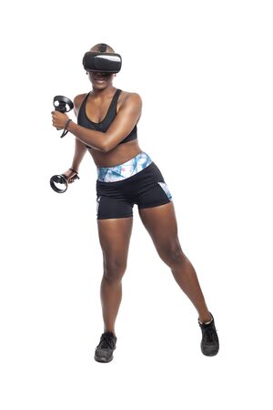 Black African American woman working out by playing a VR dancing rhythm video game while wearing a virtual reality headset.  Depicts esports technology and active lifestyle.の写真素材
