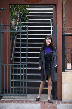 Young female college student going down the stairs from a rented apartment or condo dorm into the street looking independent.  Depicts urban and city lifestyle and housing rent.の写真素材
