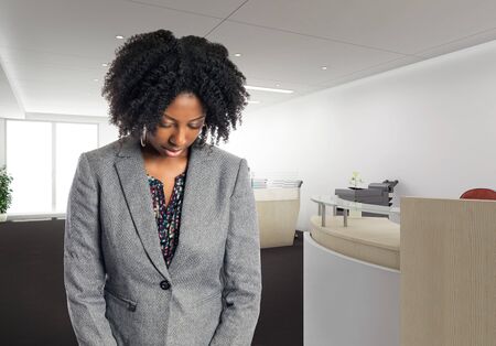 Black African American businesswoman in an office looking sad or depressed.  She is an owner or an executive of the workplace.  Depicts careers and startup business.の写真素材