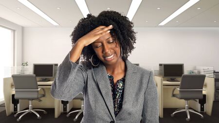 Black African American businesswoman in an office suffering from a headache.  She is an owner or an executive of the workplace.  Depicts careers and startup business.の写真素材
