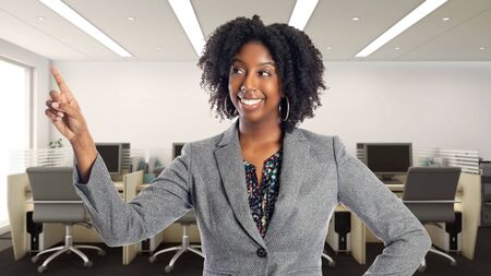 Black African American businesswoman in an office advertising or presenting something.  She is an owner or an executive of the workplace.  Depicts careers and startup business.の写真素材