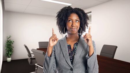 Black African American businesswoman in an office advertising or presenting something.  She is an owner or an executive of the workplace.  Depicts careers and startup business.の写真素材