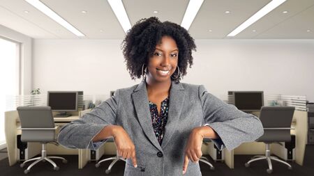 Black African American businesswoman in an office advertising or presenting something.  She is an owner or an executive of the workplace.  Depicts careers and startup business.の写真素材