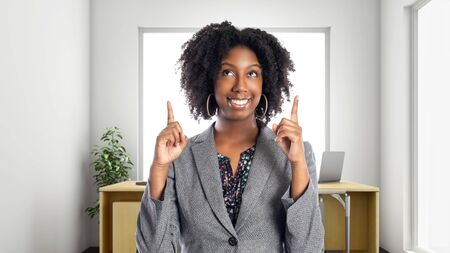 Black African American businesswoman in an office advertising or presenting something.  She is an owner or an executive of the workplace.  Depicts careers and startup business.の写真素材