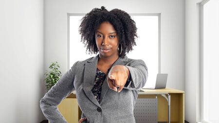 Black African American businesswoman in an office pointing forward.  She is an owner or an executive of the workplace.  Depicts careers and startup business.の写真素材