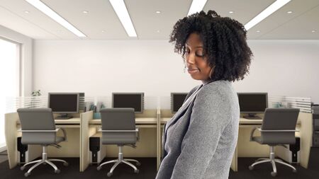 Black African American businesswoman in an office looking shy.  She is an owner or an executive of the workplace.  Depicts careers and startup business.の写真素材