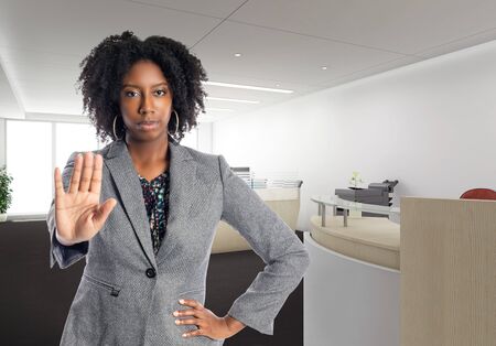 Black African American businesswoman in an office with a stop gesture.  She is an owner or an executive of the workplace.  Depicts careers and startup business.の写真素材