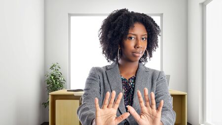Black African American businesswoman in an office with a stop gesture.  She is an owner or an executive of the workplace.  Depicts careers and startup business.の写真素材