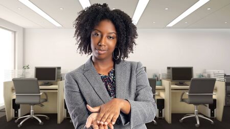 Black African American businesswoman in an office doing a money gesture.  She is an owner or an executive of the workplace.  Depicts careers and startup business.の写真素材