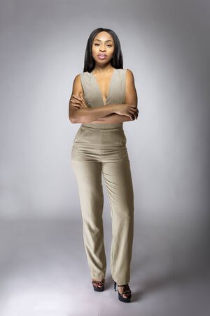 Beautiful black African American fashion model posing with humus grey or khaki clothing in a studio for fall collection catalog.  She is confidently showing the sleeveless top and matching pants.  の写真素材