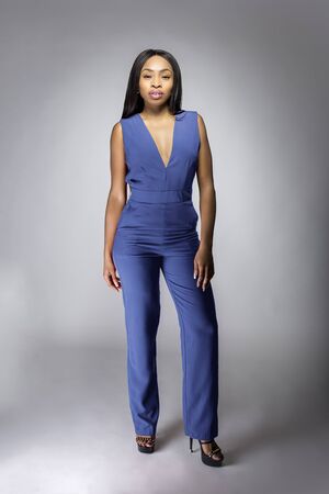 African American fashion model posing with royal or navy blue v-neck jumpsuit outfit in a studio for fall collection catalog.  She is confidently showing the sleeveless top and matching pants.の写真素材