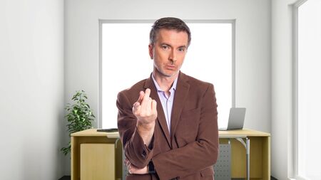 Middle-Aged businessman with gray hair and wearing a brown jacket standing in an office.  Depicts startup and corporate business.  He is pointing forward.の写真素材