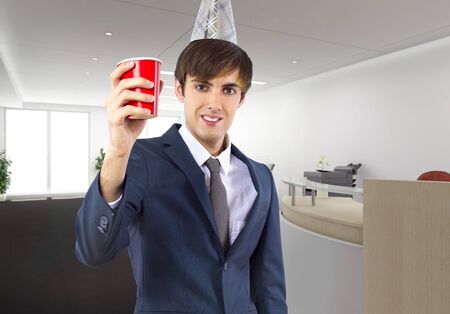 Businessman celebrating by himself alone in the office.  He is happy because of a birthday, holiday or a successful job and a pay raise.  Depicts business and success. の写真素材