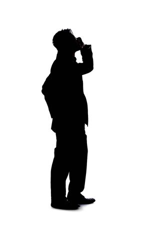 Full body silhouette of a businessman isolated on a white background. He is using a cell phone or mobile device to talk or send messages.の写真素材