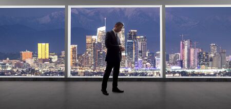 Businessman wearing a suit looking at the buildings of downtown Los Angeles from an office window.  The man looks like a politician like a mayor, or an architect or a real estate developer working in LA.の写真素材