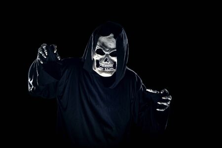 Scary monster or grim reaper ghost coming out of the dark shadows to haunt during Halloween.  Depicts a scary and deadly fictitious demonの写真素材