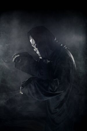 Scary looking grim reaper ghost coming out of the foggy mist.  The haunting creepy demon depicts death and evil and is a common Halloween theme as well as Day of the Dead.の写真素材