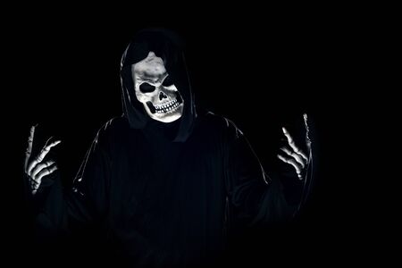 Scary monster or grim reaper ghost coming out of the dark shadows to haunt during Halloween.  Depicts a scary and deadly fictitious demonの写真素材