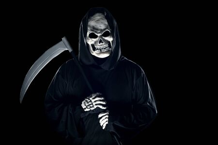Grim Reaper ghost coming out of the shadows with a scythe or sickle.  The scary demon or monster depicts Halloween and Day of the Dead holiday.の写真素材