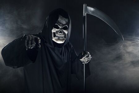 Scary looking grim reaper ghost wielding a scythe or sickle coming out of the fog.  The haunting monster depicts death and evil and is a common Halloween theme.の写真素材