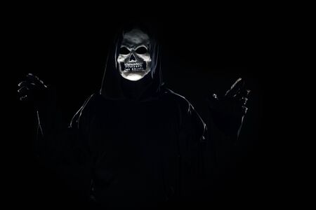 Scary monster or grim reaper ghost coming out of the dark shadows to haunt during Halloween.  Depicts a scary and deadly fictitious demonの写真素材
