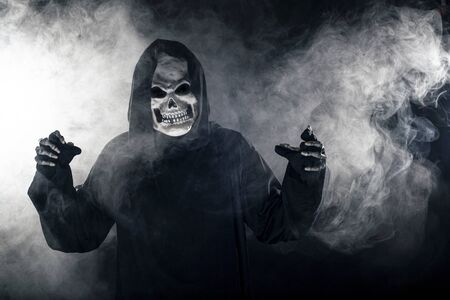 Scary looking grim reaper ghost coming out of the foggy mist.  The haunting creepy demon depicts death and evil and is a common Halloween theme as well as Day of the Dead.の写真素材