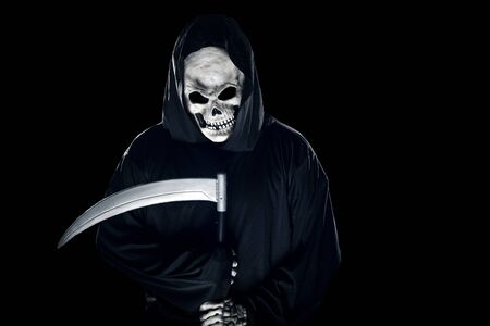 Grim Reaper ghost coming out of the shadows with a scythe or sickle.  The scary demon or monster depicts Halloween and Day of the Dead holiday.の写真素材