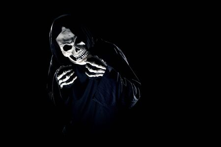 Scary monster or grim reaper ghost coming out of the dark shadows to haunt during Halloween.  Depicts a scary and deadly fictitious demonの写真素材