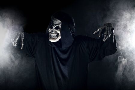 Scary looking grim reaper ghost coming out of the foggy mist.  The haunting creepy demon depicts death and evil and is a common Halloween theme as well as Day of the Dead.の写真素材