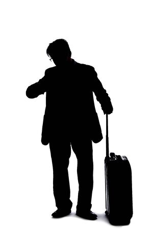 Silhouette of a businessman going on a business trip and traveling with luggage.  The man is carrying bags like preparing to board a flight at an airport.の写真素材