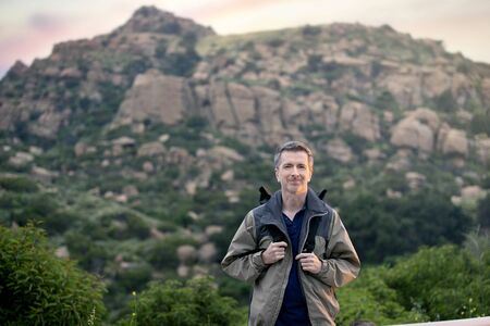 Middle aged man staying healthy by doing outdoor activities during a nature getaway vacation.  He is hiking through the mountains and enjoying the peace and serenity. の写真素材