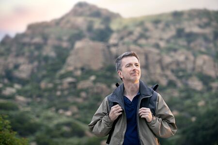 Middle aged man staying healthy by doing outdoor activities during a nature getaway vacation.  He is hiking through the mountains and enjoying the peace and serenity.の写真素材