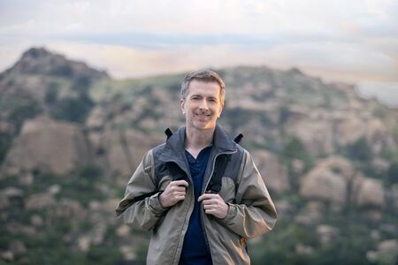 Middle aged man staying healthy by doing outdoor activities during a nature getaway vacation.  He is hiking through the mountains and enjoying the peace and serenity.の写真素材