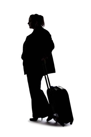 Silhouette of a businesswoman going on a business trip and traveling with luggage.  She is carrying bags like preparing to board a flight at an airport.の写真素材