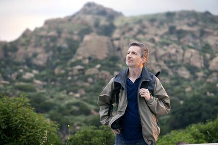 Middle aged man staying healthy by doing outdoor activities during a nature getaway vacation.  He is hiking through the mountains and enjoying the peace and serenity.の写真素材