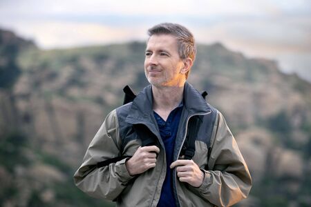 Middle aged man staying healthy by doing outdoor activities during a nature getaway vacation.  He is hiking through the mountains and enjoying the peace and serenity.の写真素材