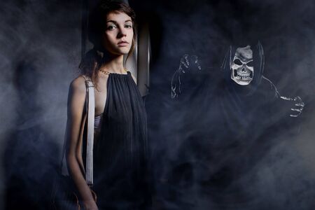 Woman in a dark alley with fog or mist imagining or seeing a demon or ghost.  Depicts a horrifying nightmare or hallucinations due to mental illness の写真素材