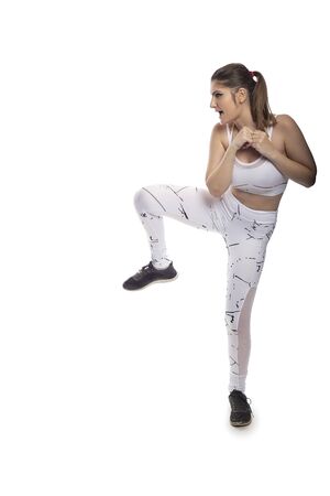 Woman showing core strength by balancing while kicking.  She is training for kick boxing or mma combat sport or working out with cardio exercises.の写真素材