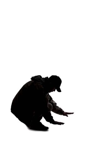 Silhouette of a male hiker or explorer isolated on a white background wearing a hat and clothes for trekking. He is searching or looking for something on the groundの写真素材