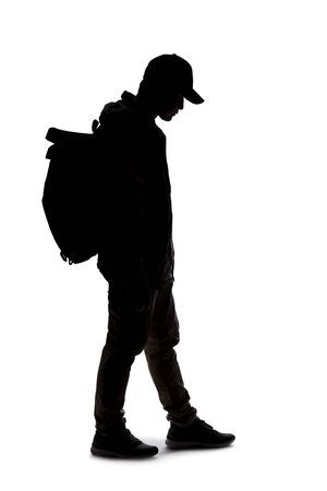 Silhouette of a man wearing a backpack looking like a traveler or hiker trekking.  He is patiently standing and waiting の写真素材