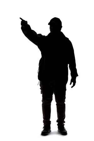 Silhouette of a man wearing a backpack looking like a traveler or hiker trekking.  He is pointing at somethingの写真素材