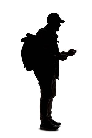 Silhouette of a man wearing a backpack looking like a traveler or hiker trekking.  He is gesturing like he is talking or speakingの写真素材