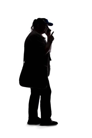 Silhouette of a curvy or plus size woman on a white background.  She is unrecognizable and using a cell phone or smartphoneの写真素材